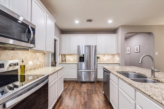 kitchen with appliances with stainless steel finishes, sink, light stone counters, and white cabinets