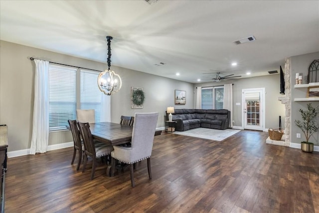 dining space featuring dark hardwood / wood-style flooring, ceiling fan with notable chandelier, and a wealth of natural light