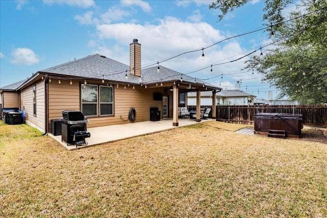 rear view of house with a patio area, a yard, and a hot tub