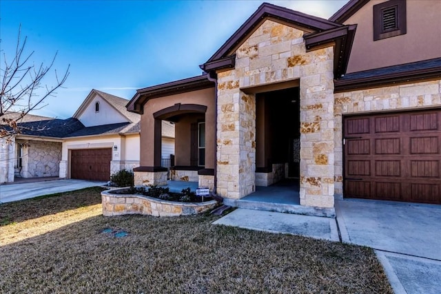 property entrance featuring stone siding, stucco siding, driveway, and a garage