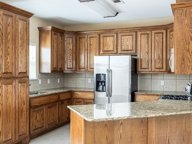 1504 County Road 459, Thorndale, TX 76577 - kitchen with stainless steel fridge with ice dispenser, brown cabinets, and decorative backsplash