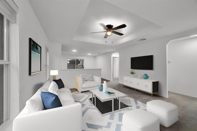 living room with ceiling fan, a tray ceiling, and carpet floors