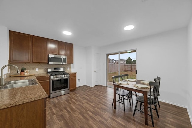 kitchen featuring stainless steel appliances, sink, backsplash, and dark hardwood / wood-style floors