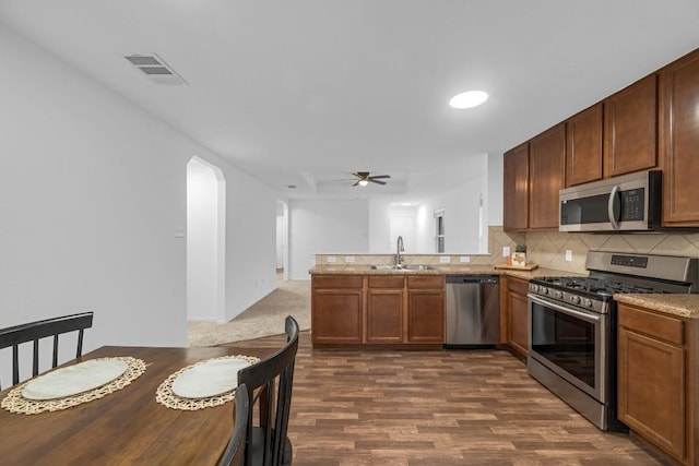 kitchen with sink, stainless steel appliances, dark hardwood / wood-style flooring, decorative backsplash, and kitchen peninsula