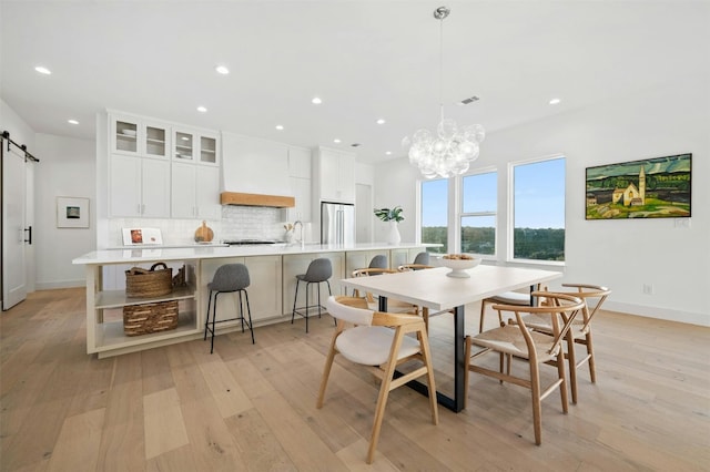 dining space with an inviting chandelier, light hardwood / wood-style flooring, and a barn door