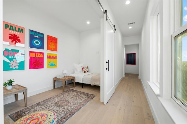 hallway with a barn door and light wood-type flooring