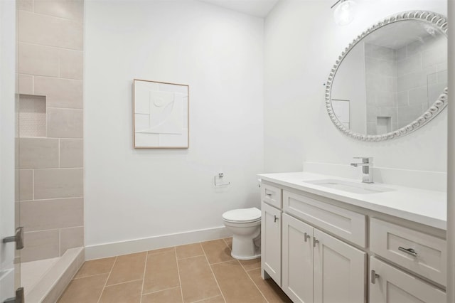 bathroom featuring tiled shower, tile patterned floors, vanity, and toilet