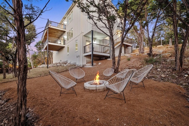 back house at dusk with a balcony and an outdoor fire pit