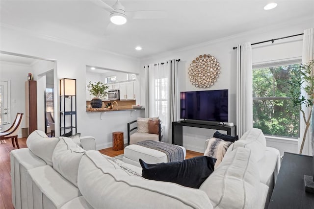 living room with baseboards, ceiling fan, wood finished floors, crown molding, and recessed lighting