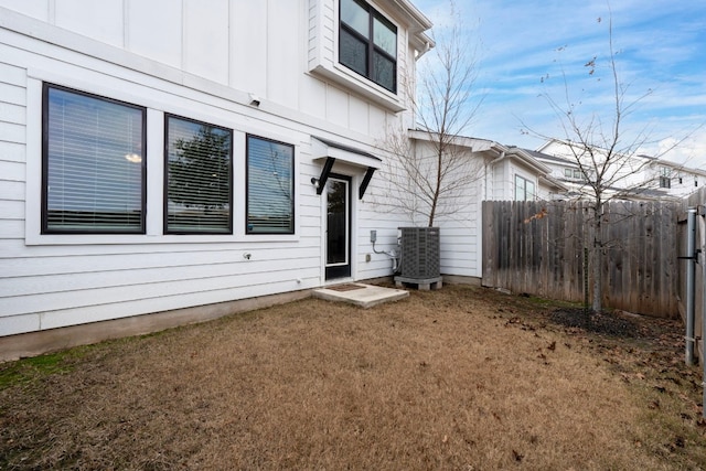 back of property with central AC unit and a lawn