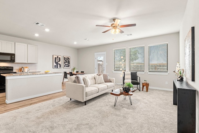 living room featuring light carpet and ceiling fan