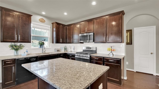 kitchen with a kitchen island, appliances with stainless steel finishes, sink, and light stone counters