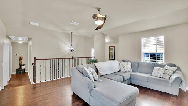 living room with attic access, lofted ceiling, dark wood-style flooring, and visible vents