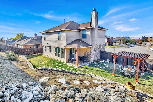 back of property with a fenced backyard, a patio, a chimney, and a lawn