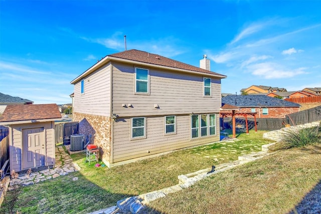 back of house featuring cooling unit, a storage shed, and a lawn