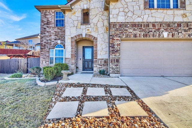 view of front of home featuring stone siding, fence, concrete driveway, and brick siding