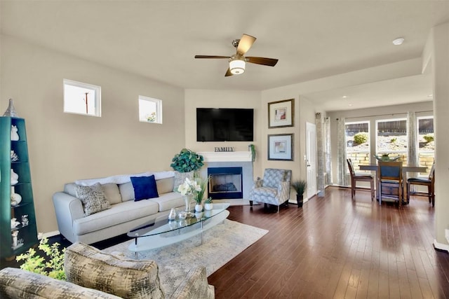 living room with a ceiling fan, a fireplace, dark wood finished floors, and baseboards