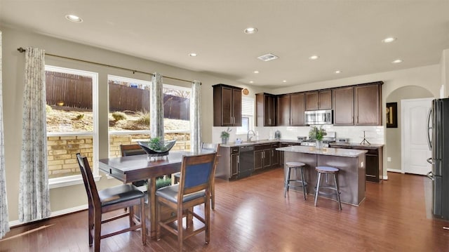 kitchen featuring sink, dark wood-type flooring, appliances with stainless steel finishes, dark brown cabinetry, and a kitchen island