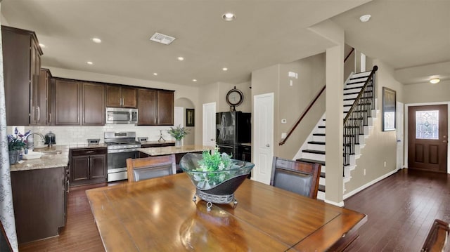 dining room with arched walkways, dark wood-style flooring, visible vents, and stairway