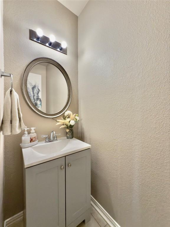 bathroom with a textured wall, vanity, and baseboards