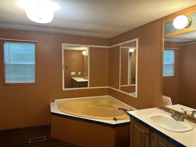 bathroom featuring vanity, hardwood / wood-style flooring, a tub, and a textured ceiling