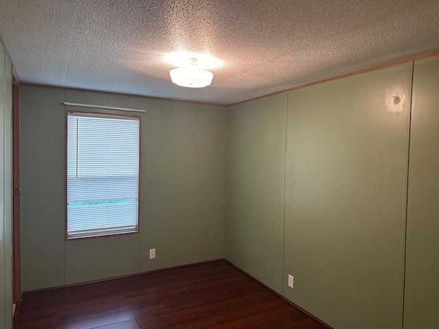 spare room with dark wood-type flooring and a textured ceiling