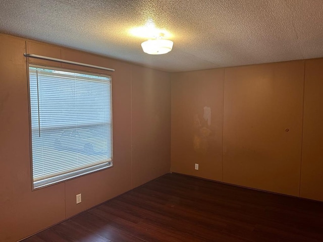 unfurnished room featuring dark hardwood / wood-style flooring and a textured ceiling