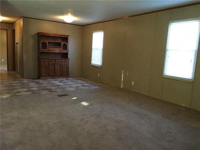 unfurnished living room featuring ornamental molding and carpet