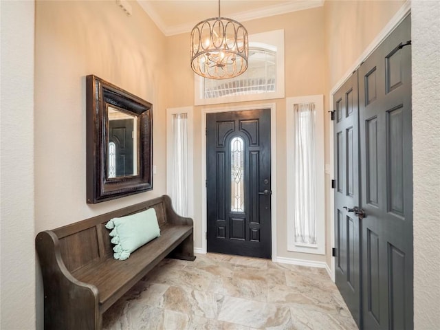 foyer featuring a towering ceiling, marble finish floor, an inviting chandelier, crown molding, and baseboards