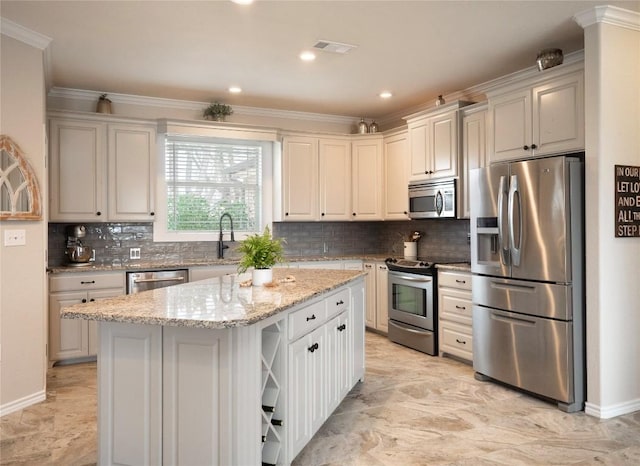 112 Chaumont St, Kingsland, TX 78639 - kitchen with appliances with stainless steel finishes, ornamental molding, a sink, a kitchen island, and light stone counters