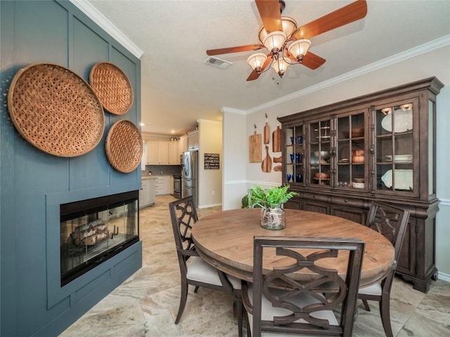 112 Chaumont St, Kingsland, TX 78639 - dining space featuring ceiling fan, crown molding, baseboards, and a tiled fireplace