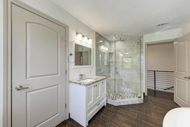 bathroom featuring a shower with door, vanity, and a textured ceiling