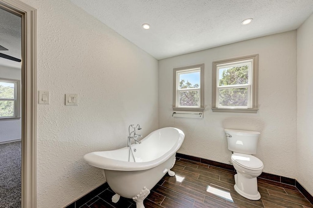 bathroom featuring a bathing tub, a textured ceiling, and toilet