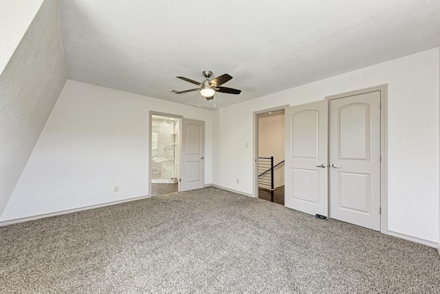 unfurnished bedroom with ceiling fan, ensuite bath, and carpet