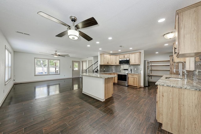 kitchen featuring sink, stainless steel appliances, light stone countertops, light brown cabinetry, and decorative backsplash