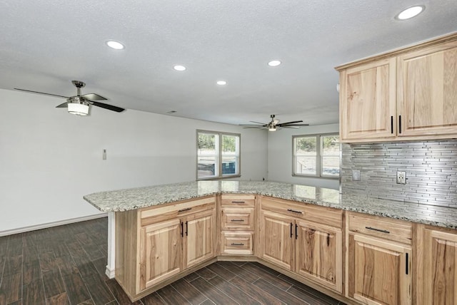 kitchen with ceiling fan, tasteful backsplash, light stone counters, light brown cabinetry, and kitchen peninsula