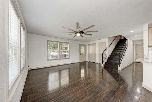 unfurnished living room featuring ceiling fan, dark hardwood / wood-style flooring, and a textured ceiling