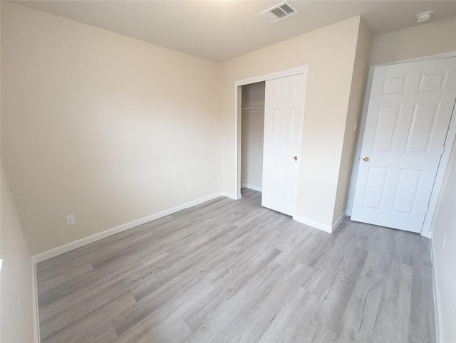 unfurnished bedroom featuring light wood-type flooring and a closet