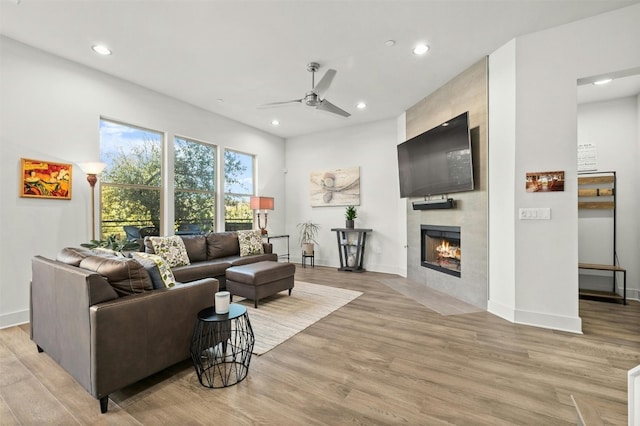 living room featuring recessed lighting, a tile fireplace, light wood-type flooring, baseboards, and ceiling fan