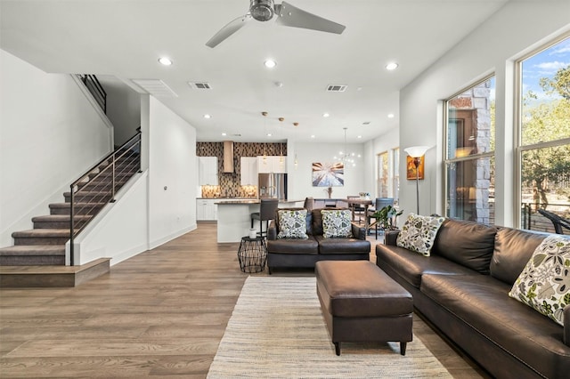 living room with light wood-type flooring, a ceiling fan, visible vents, and recessed lighting