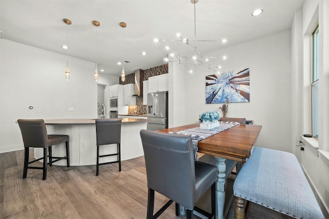 dining area with a notable chandelier, wood finished floors, and recessed lighting