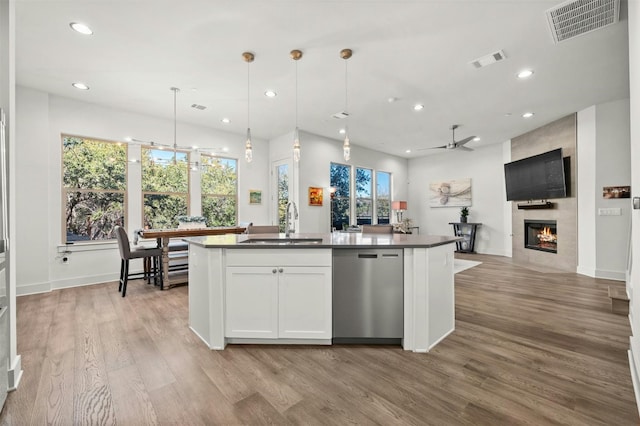 kitchen featuring a sink, open floor plan, dishwasher, a tiled fireplace, and visible vents