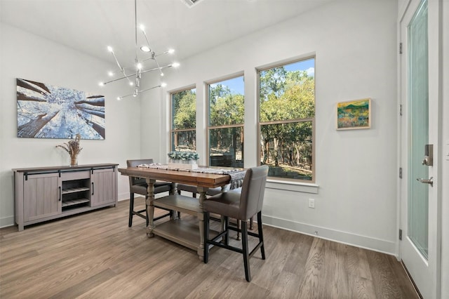 dining space featuring baseboards, a notable chandelier, and wood finished floors