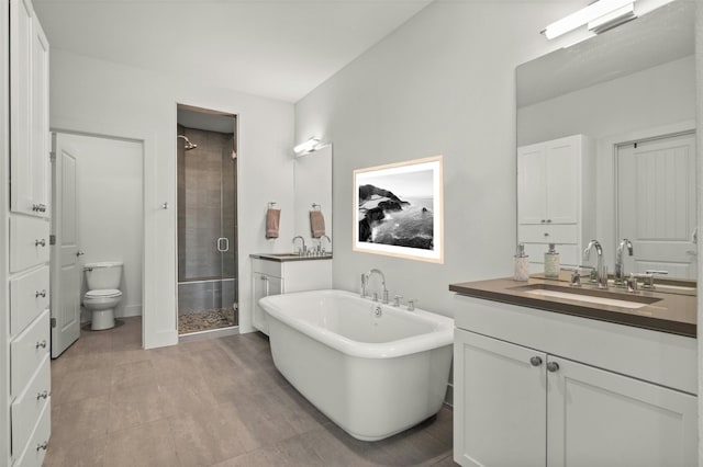 full bathroom with a shower stall, a freestanding tub, toilet, and vanity