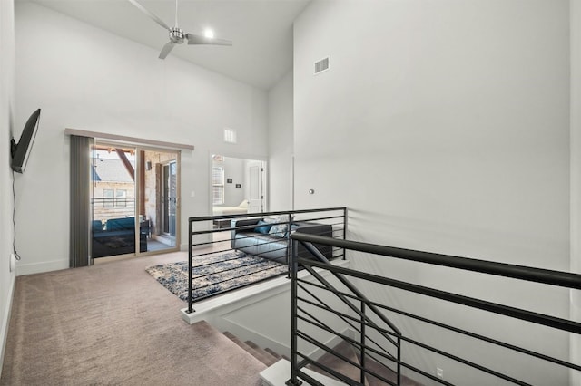 staircase featuring visible vents, baseboards, carpet flooring, and high vaulted ceiling