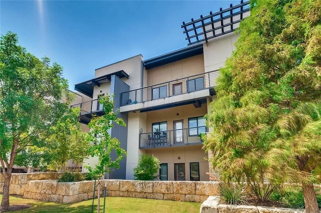 rear view of property featuring a yard and stucco siding