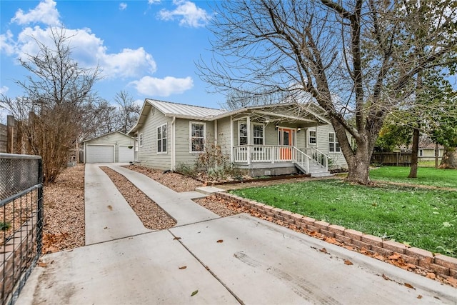 view of front of home with an outbuilding, a garage, covered porch, and a front yard