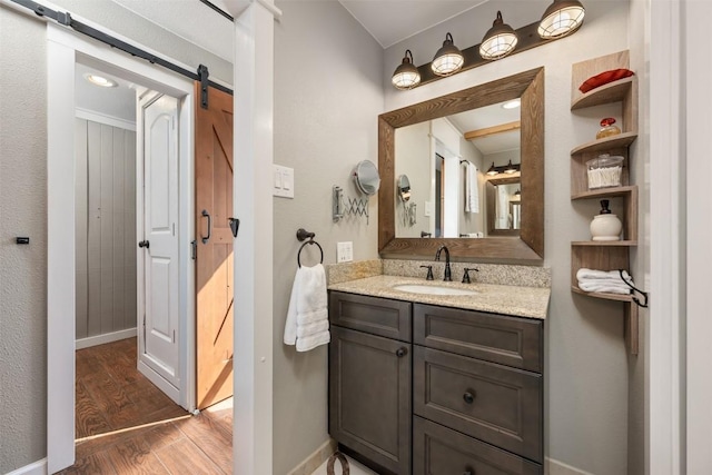 bathroom with vanity, wood finished floors, and baseboards