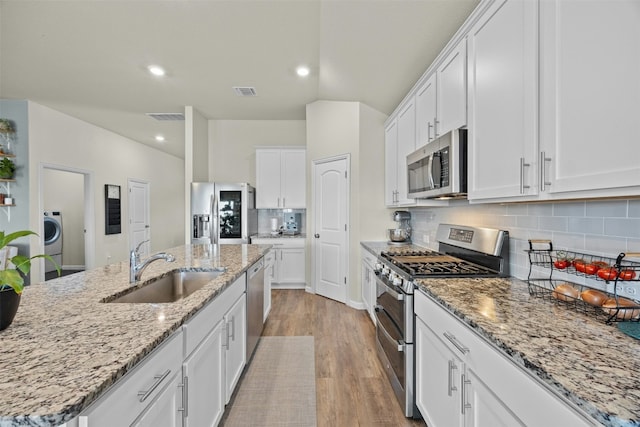 kitchen featuring white cabinetry, stainless steel appliances, a kitchen island with sink, and sink