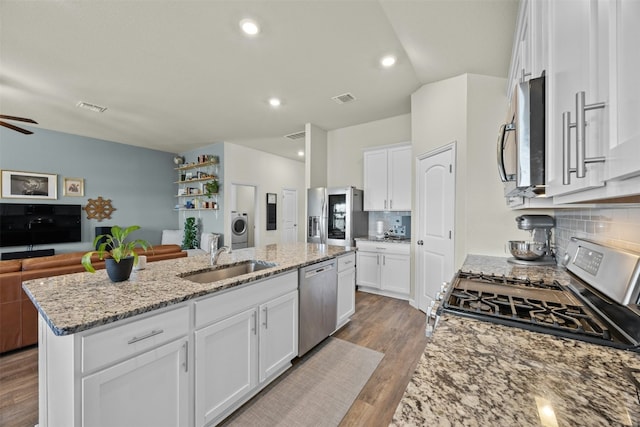 kitchen with white cabinetry, sink, a kitchen island with sink, light stone counters, and stainless steel appliances